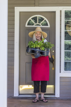 Caucasian woman holding potted plants in doorway
