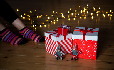 Fototapeta na wymiar red gift boxes feet and christmas lights on wooden floor