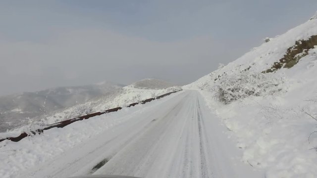 POV drive on snow covered mountain rural road