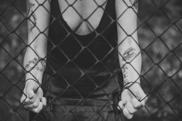 beautiful young woman poses sensually near a metal mesh