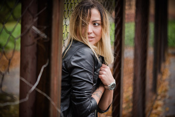 beautiful young woman poses sensually near a metal mesh