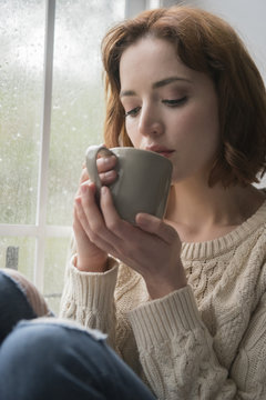 Woman Drinking Coffee Near Rainy Window