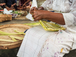 Old woman making bamboo baskets called canang sari in a local temple in Ubud for Nyepi Festival
