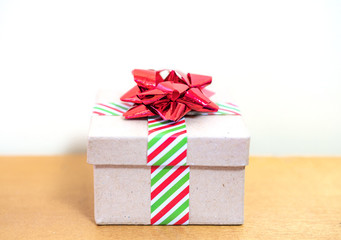 Closeup of vintage cardboard gift box wrapped in striped holiday ribbon and shiny elegant bow