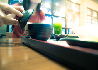 Woman is playing smartphone in Japanese resturant during lunch time