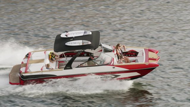 Wide high angle tracking shot of people in speedboat on lake / Lake Powell, Utah, United States