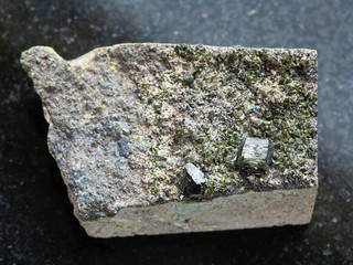 raw green crystals of Epidote on rock on dark