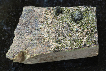 rough crystals of Epidote on rock on dark
