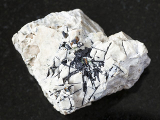 Ilmenite black crystals on rough stone on dark