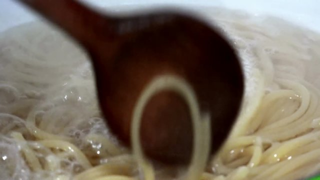Chef steering boiling spagethi pasta in a pot, closeup