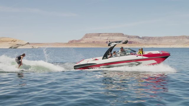 Wide tracking shot of boat pulling wake surfer / Lake Powell, Utah, United States