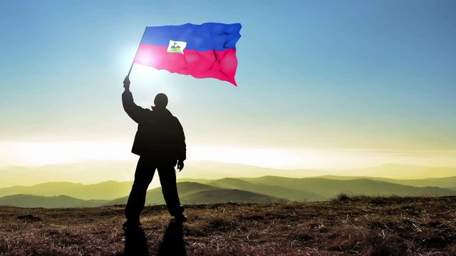 Successful silhouette man winner waving Haiti flag on top of the mountain peak. Cinemagraph LOOP background