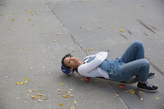 Young woman lying on skateboard outdoors