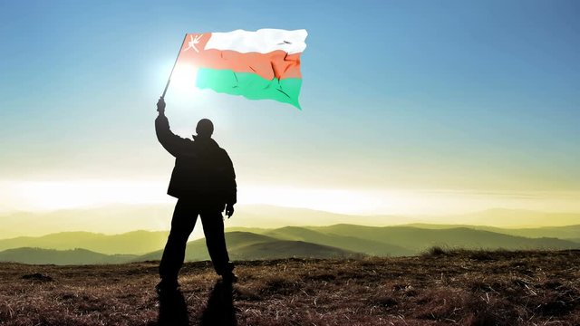 Successful silhouette man winner waving Oman flag on top of the mountain peak, Cinemagraph LOOP background
