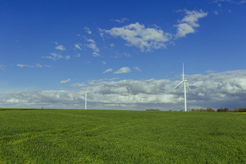 Wind turbines of a power plant for electricity generation in Normandy, France. Concept of renewable sources of energy. Country sunny landscape. Environmentally friendly electricity production. Toned