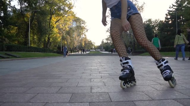 Young attractive woman in sexy tights slalom rollerblading in park on a beautiful sunny evening.