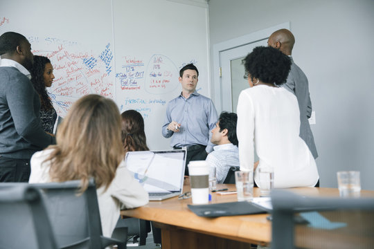 Businessman talking near whiteboard in meeting - Powered by Adobe