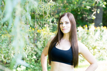 Portrait of a woman exercising in a park with beautiful green forest in background
