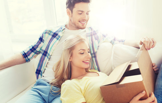smiling couple with cardboard box at home