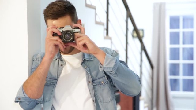 Man at home using vintage reflex camera