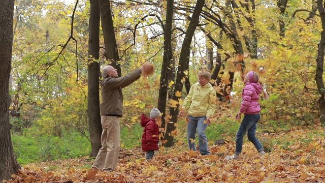 Grandparents and children with leaves in autumn