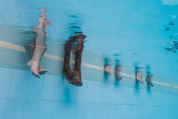 Feet of four women underwater in a pool