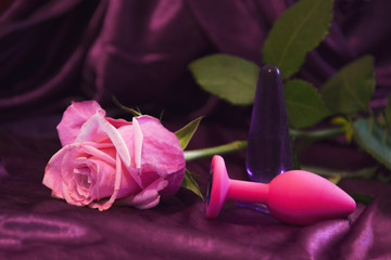 Silicone dildo Sex toy and a pink rose on a dark background.