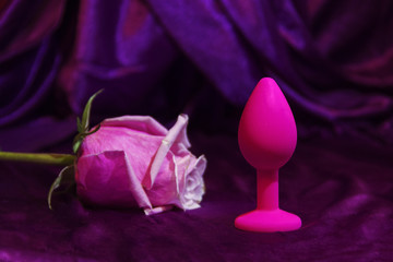Silicone dildo Sex toy and a pink rose on a dark background.