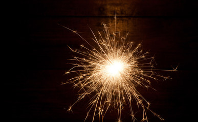 burning sparkler and christmas lights on wooden background