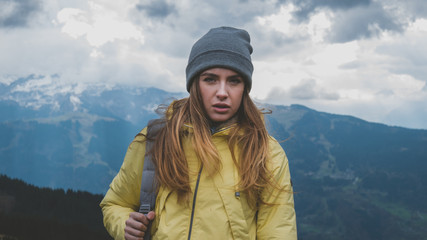 Fototapeta na wymiar Hipster young girl with backpack hiking in mountains. Tourist traveler walking on top of the mountain