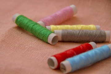 Fototapeta na wymiar Sewing threads multicolored on linen background closeup.