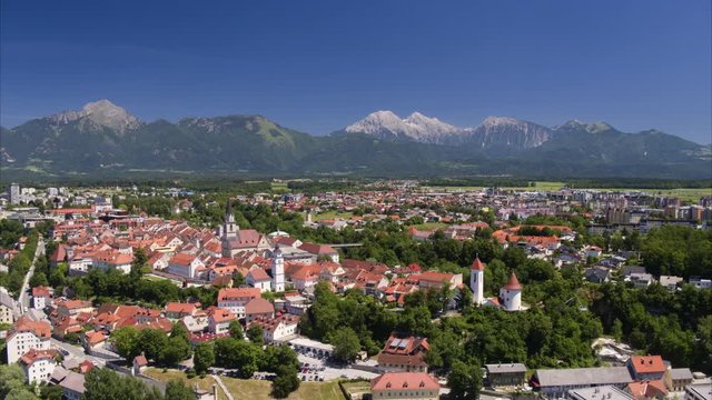 Wide aerial shot approaching village near mountain range / Kranj, Slovenia