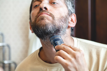 Grooming beard. Man alone strizhёt beard in bathroom