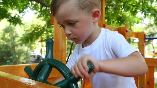 The child plays with great pleasure on the playground with a toy sea wheel.