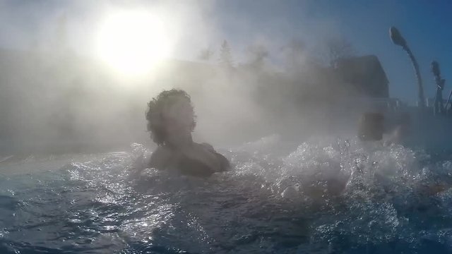 Young woman relaxing in the thermal spa water pool outdoors, SLOW MOTION
