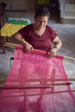 Senior woman weaving fabric on loom