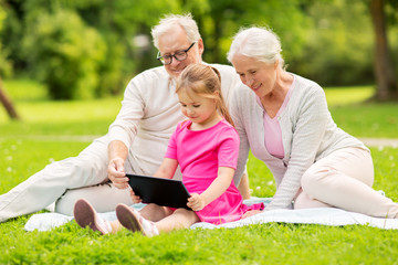 grandparents and granddaughter with tablet pc