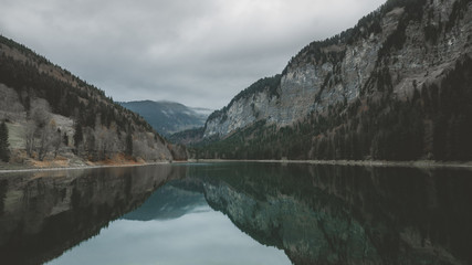 Wide angle view of Montriond Lake on a rainy day, mountains in the background. French Alps