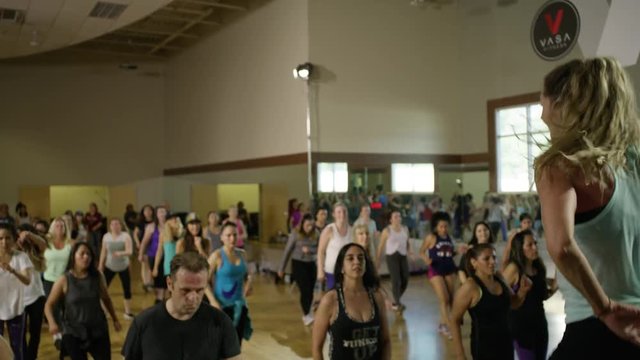 Medium panning shot of fitness instructor leading exercise class / Orem, Utah, United States