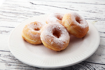 powdered sugar donuts on rustic white table.