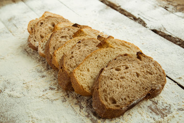 Sliced pieces of bread on wooden table with flour