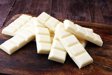 white chocolate bars and white choco pieces on wood.