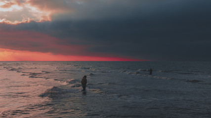 Fototapeta premium Fisherman using catching dredge for oyster fishing during sunset