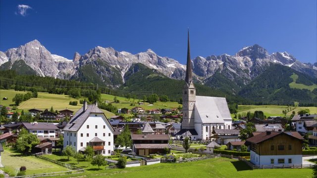 Wide aerial shot of houses and tower near mountain range / Maria Alm, Austria