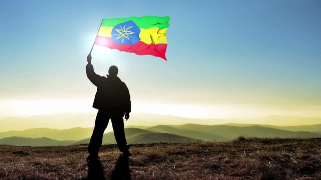 Successful silhouette man winner waving Ethiopian flag on top of the mountain peak. Cinemagraph LOOP background
