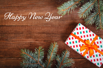 Christmas composition. Fir branches and a gift on a brown background. Space for text, top view. Background