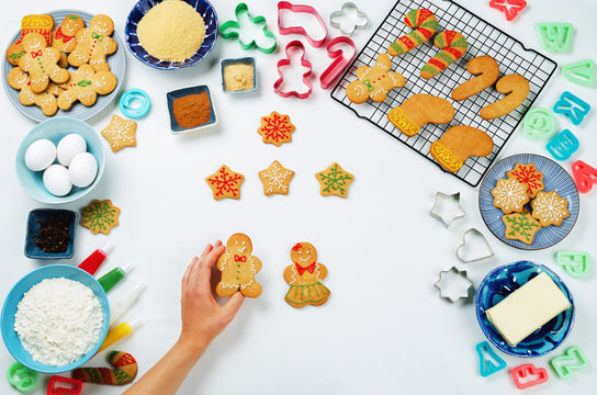 Gingerbread cookies with ingredients for baking and woman's hands