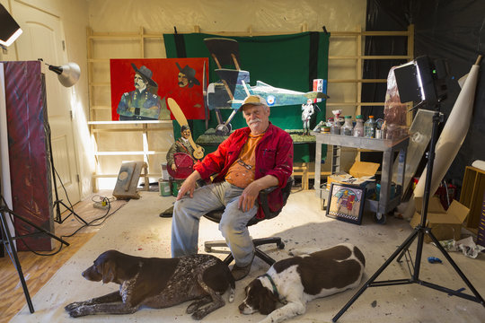 Portrait of older Caucasian man in workshop with dogs