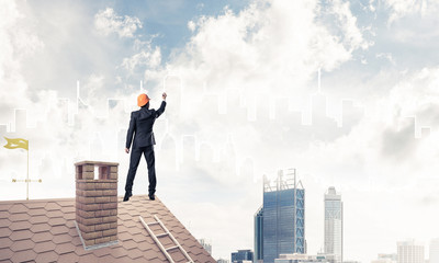 Man architect draw silhouette of modern city on blue sky. Mixed 