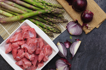 Turkey raw meat with vegetables on the black wooden table.